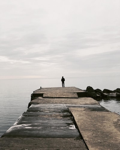 Man standing on rock at sea. Artist: Rithika Gopal. Unsplash